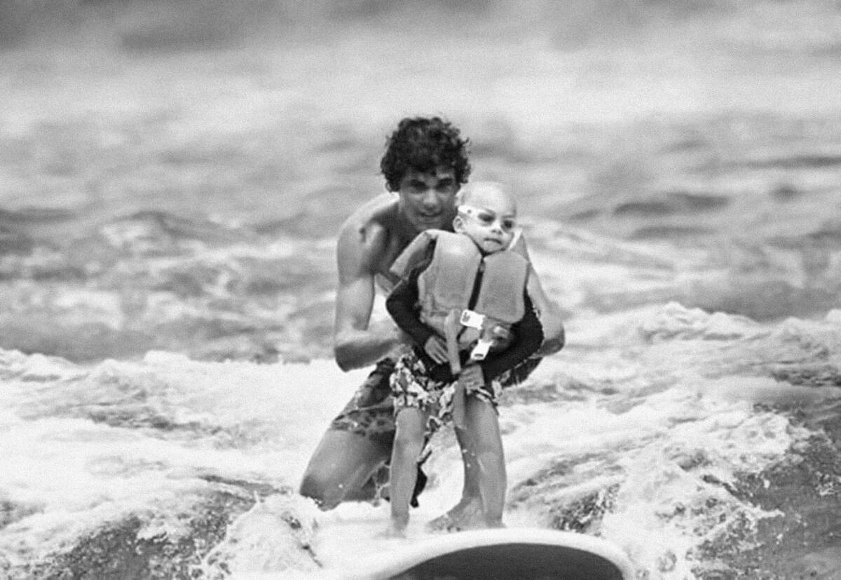 Óscar surfea con un niño en Hawái